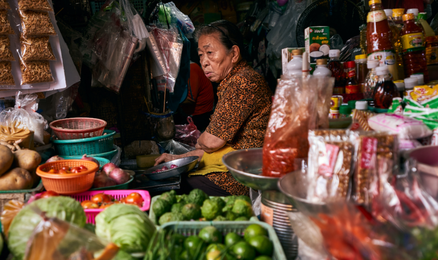 woman in a market stall surrounded by produce
