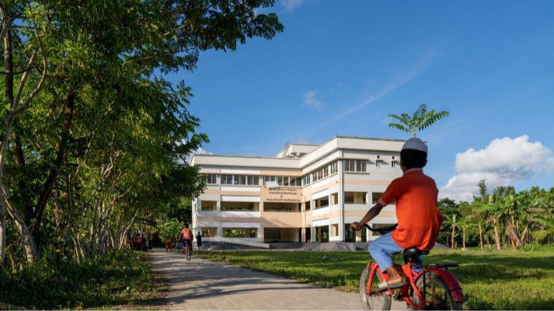 young boy on a bicycle riding toward a corporate-looking building
